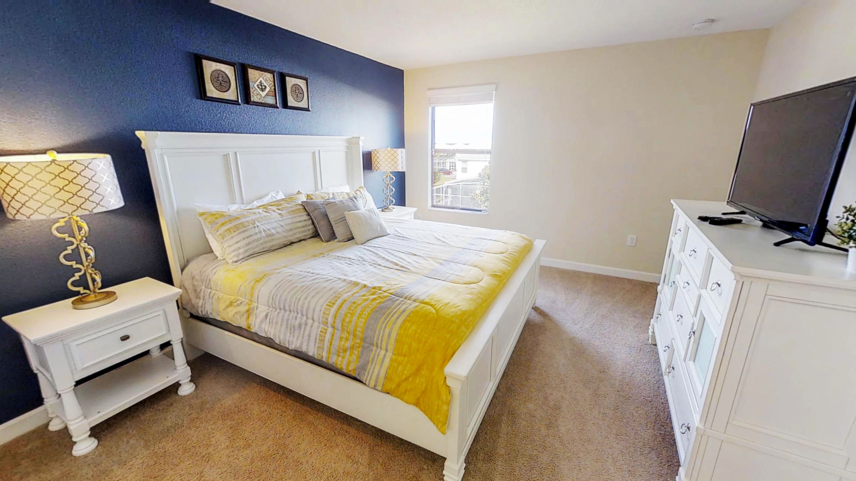A bedroom with a bed, nightstand, dresser, and TV.