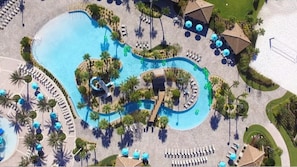 An aerial view of a resort with a large central pool, multiple smaller pools, and sun loungers arranged around the pools. - Champions Gate 9035 (Davenport)