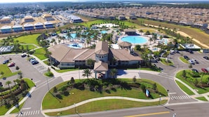 An aerial view of a residential area with multiple houses, a central swimming pool, and a parking lot. - Champions Gate 9035 (Davenport)
