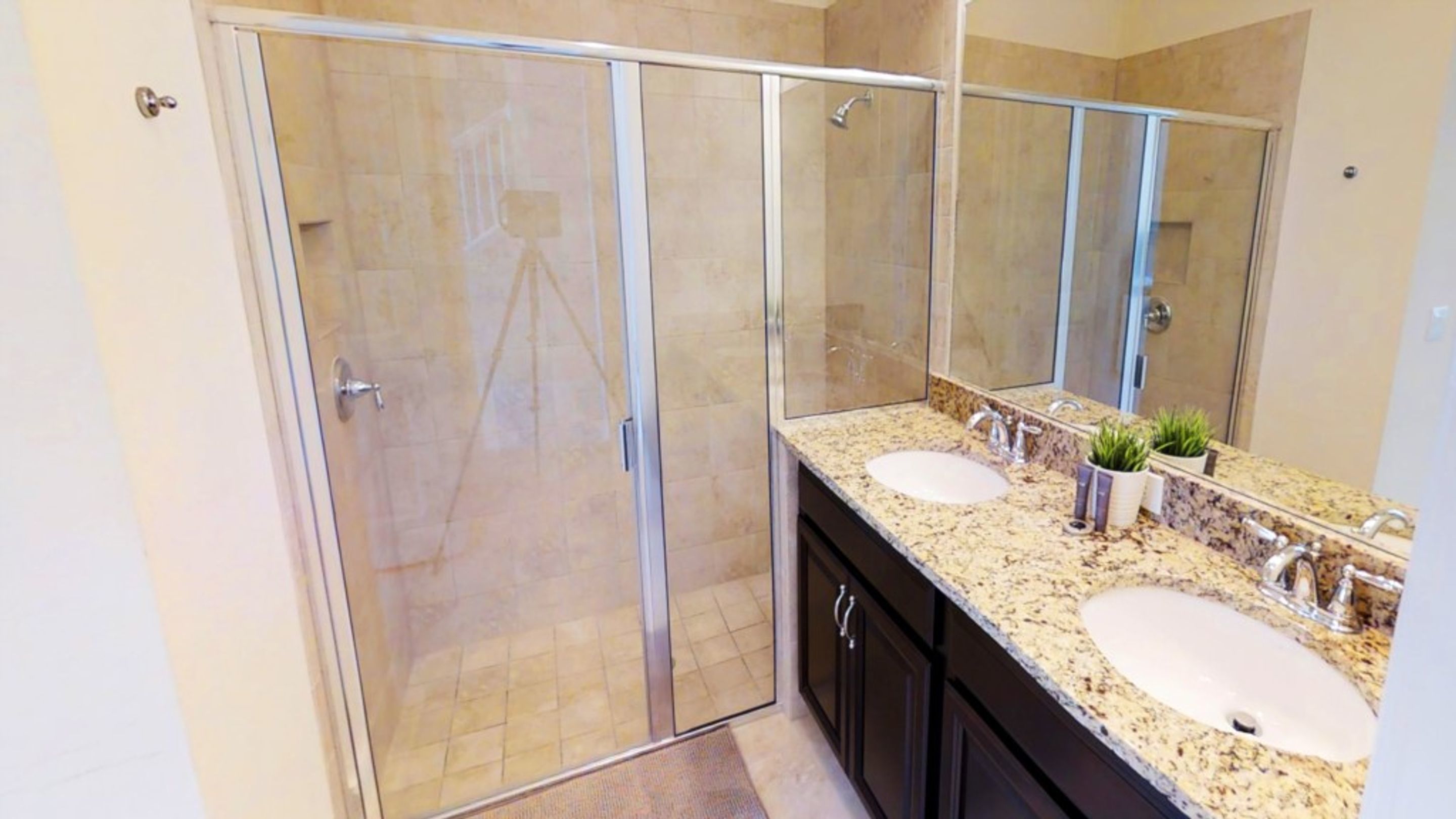 A modern bathroom with a glass shower enclosure, two sinks, and a large mirror.