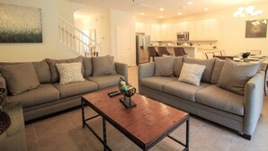 Ein Wohnzimmer mit zwei Sofas, einem Couchtisch und einer Küche im Hintergrund.