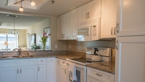 Une cuisine moderne avec des meubles blancs, un plan de travail en granit, un four à micro-ondes encastré et une cuisinière.