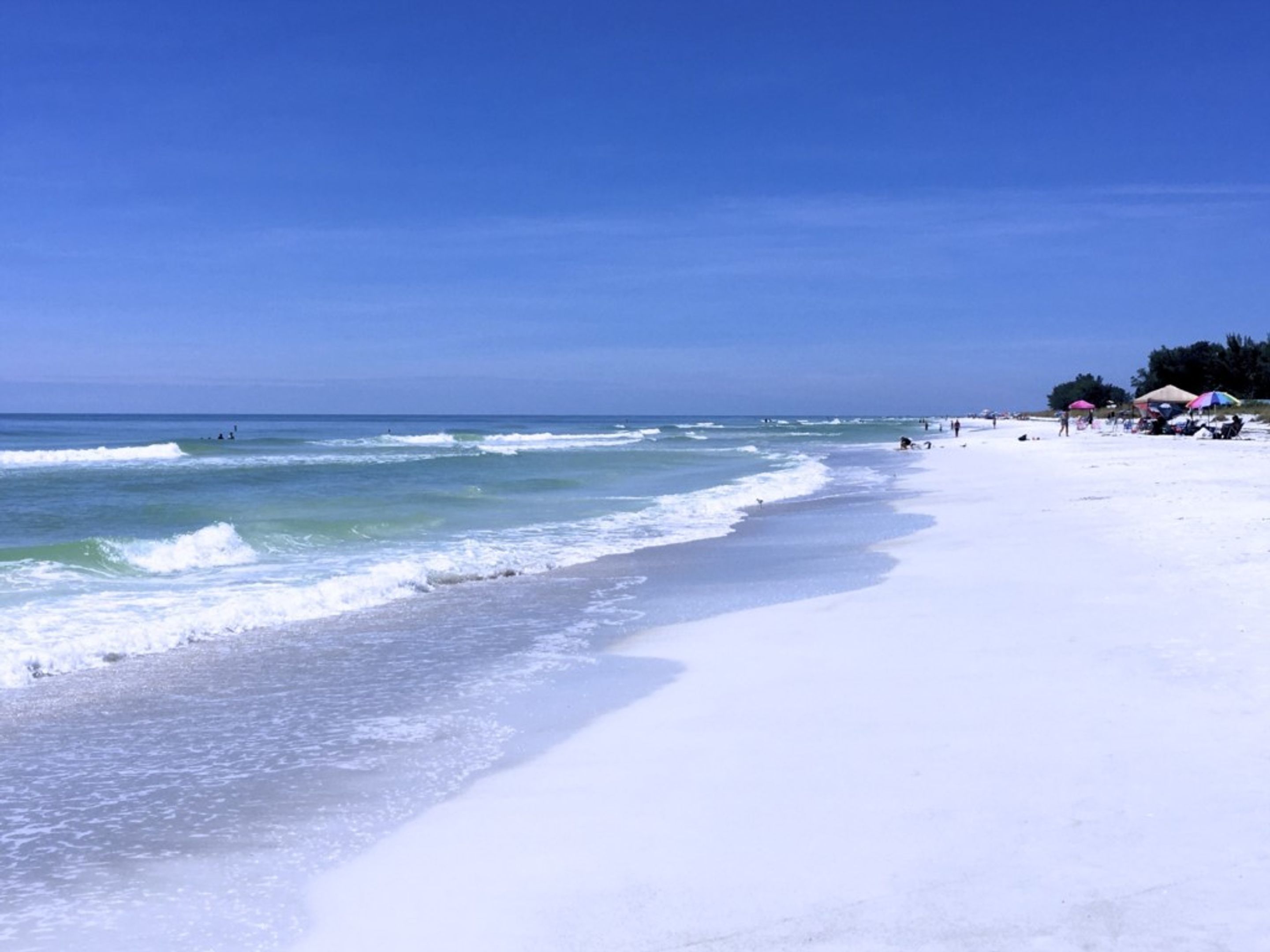 Una playa con cielos despejados y olas tranquilas.