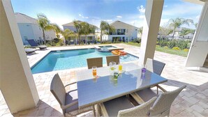 A poolside patio with a table and chairs, a swimming pool, and a view of surrounding houses. - Encore Resort at Reunion 7632 (Kissimmee)