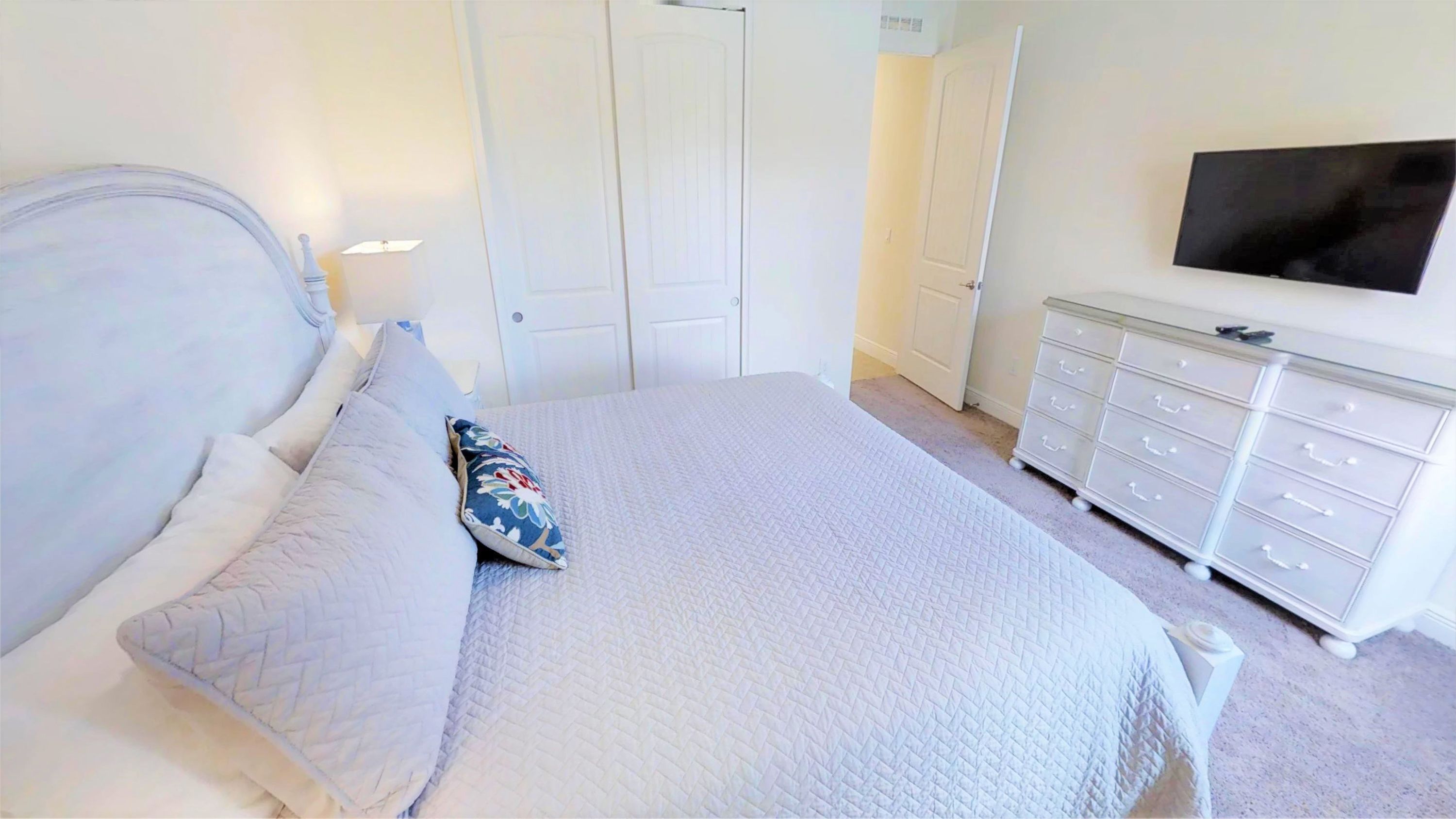 A bedroom with a bed, pillows, a dresser, and a television.