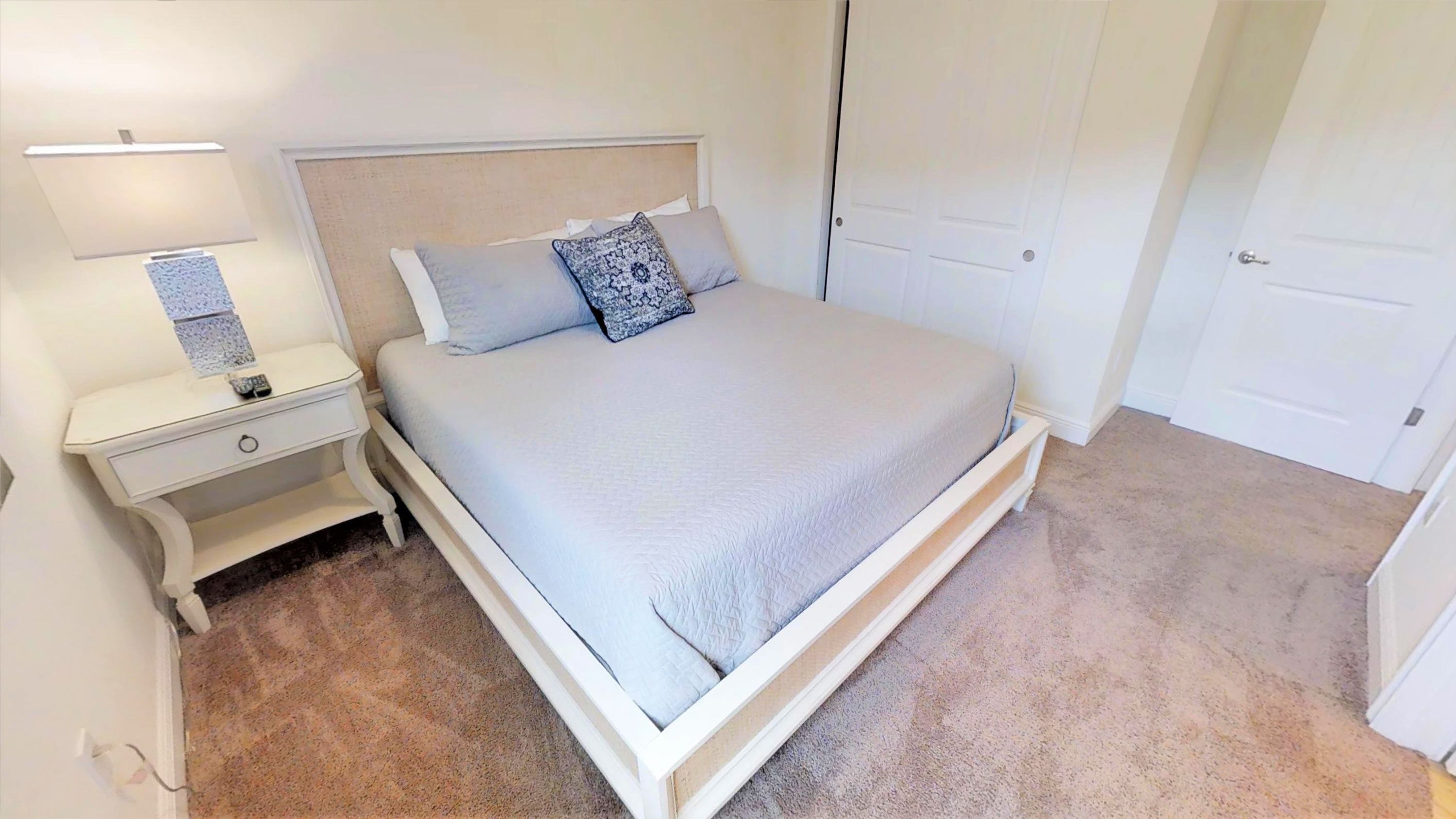 A neatly arranged bedroom with a bed, nightstands, and a door.