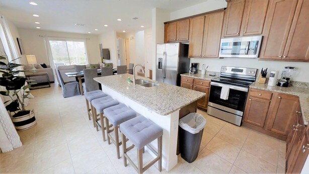 A modern kitchen with granite countertops, stainless steel appliances, and wooden cabinets. - Encore Resort at Reunion 7521 (Kissimmee)