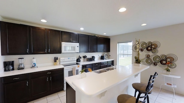 A modern kitchen with dark cabinets, a white countertop, and a central island. - Crystal Cove 947 (Kissimmee)