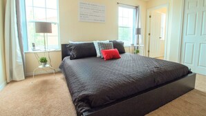 A bedroom with a large bed, two bedside tables, a window with curtains, and a wall-mounted sign with text. - Terra Verde Resort 101 (Kissimmee)