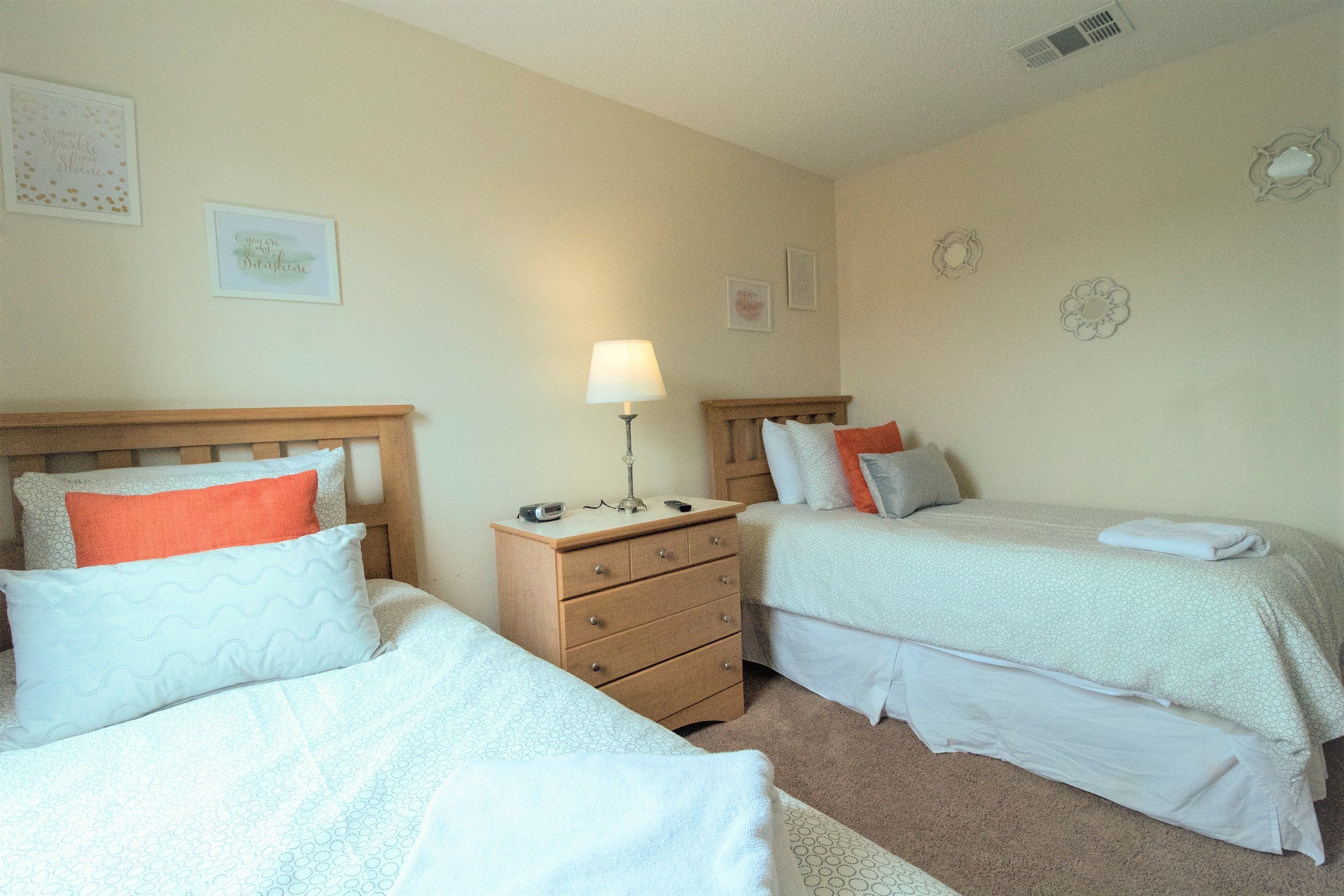 Une chambre avec deux lits, une table de chevet et une lampe.