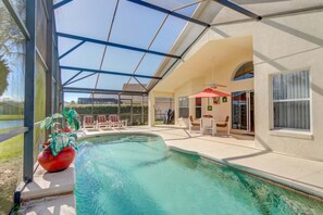 A covered swimming pool area with a glass ceiling, a red decorative planter, and outdoor seating.