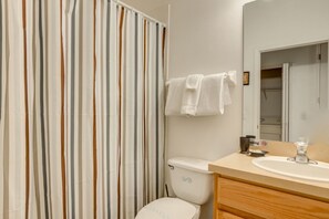A bathroom with a striped shower curtain, a toilet, a sink, and a mirror.