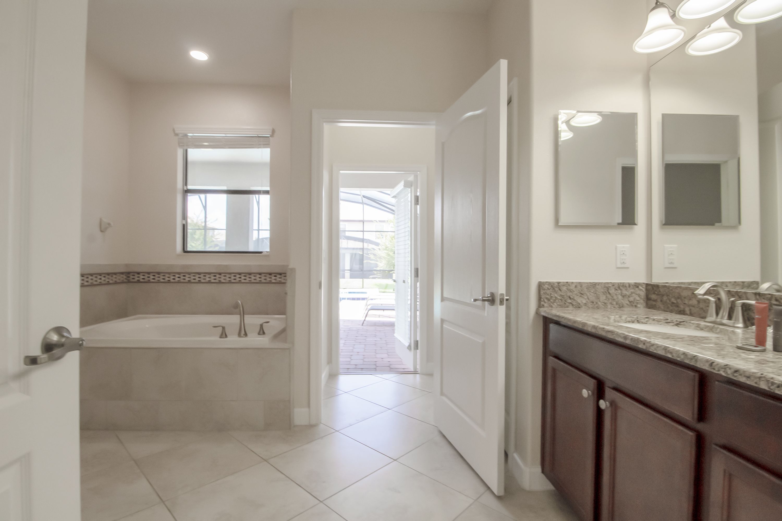A modern bathroom with a bathtub, vanity, and large mirrors.