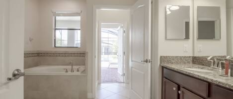 A modern bathroom with a bathtub, vanity, and large mirrors.