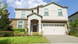 A two-story house with a garage, stone facade, and a well-maintained lawn. - Champions Gate 1476 (Davenport)