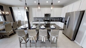 A modern kitchen with white cabinets, stainless steel appliances, and a central island with chairs.
