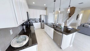 A modern kitchen with white cabinets, stainless steel appliances, and a granite countertop.