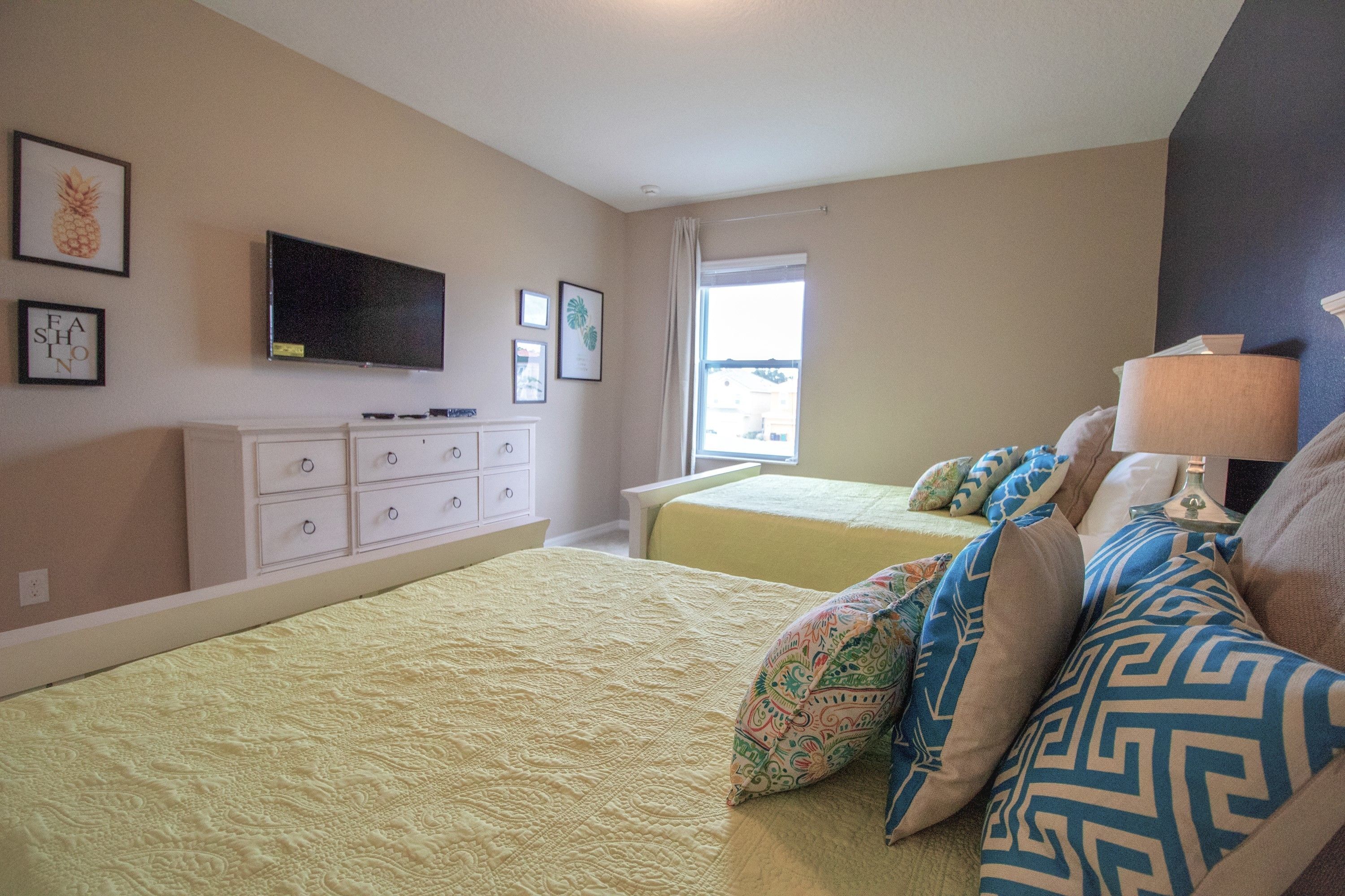 Quarto com duas camas, televisão, cômoda e janela com vista.