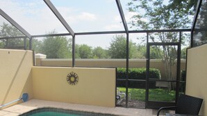 A swimming pool with a sun-shaped decoration on the wall, a patio table, and chairs. - Windsor Hills 2503 (Kissimmee)