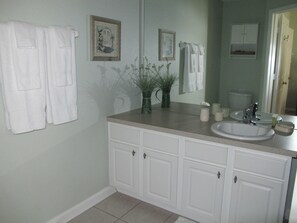 A bathroom with a white vanity, a sink, a mirror, and two framed pictures on the wall. - Windsor Hills 2503 (Kissimmee)