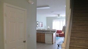 A spacious living area with a kitchen, a dining table, and a red sofa. - Windsor Hills 2503 (Kissimmee)