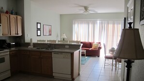 A kitchen with a dishwasher, a dining area with a table and chairs, a sofa, and a ceiling fan. - Windsor Hills 2503 (Kissimmee)