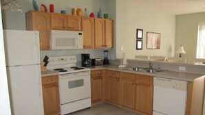 A kitchen with wooden cabinets, a white refrigerator, a microwave, a stove, and a dishwasher. - Windsor Hills 2503 (Kissimmee)