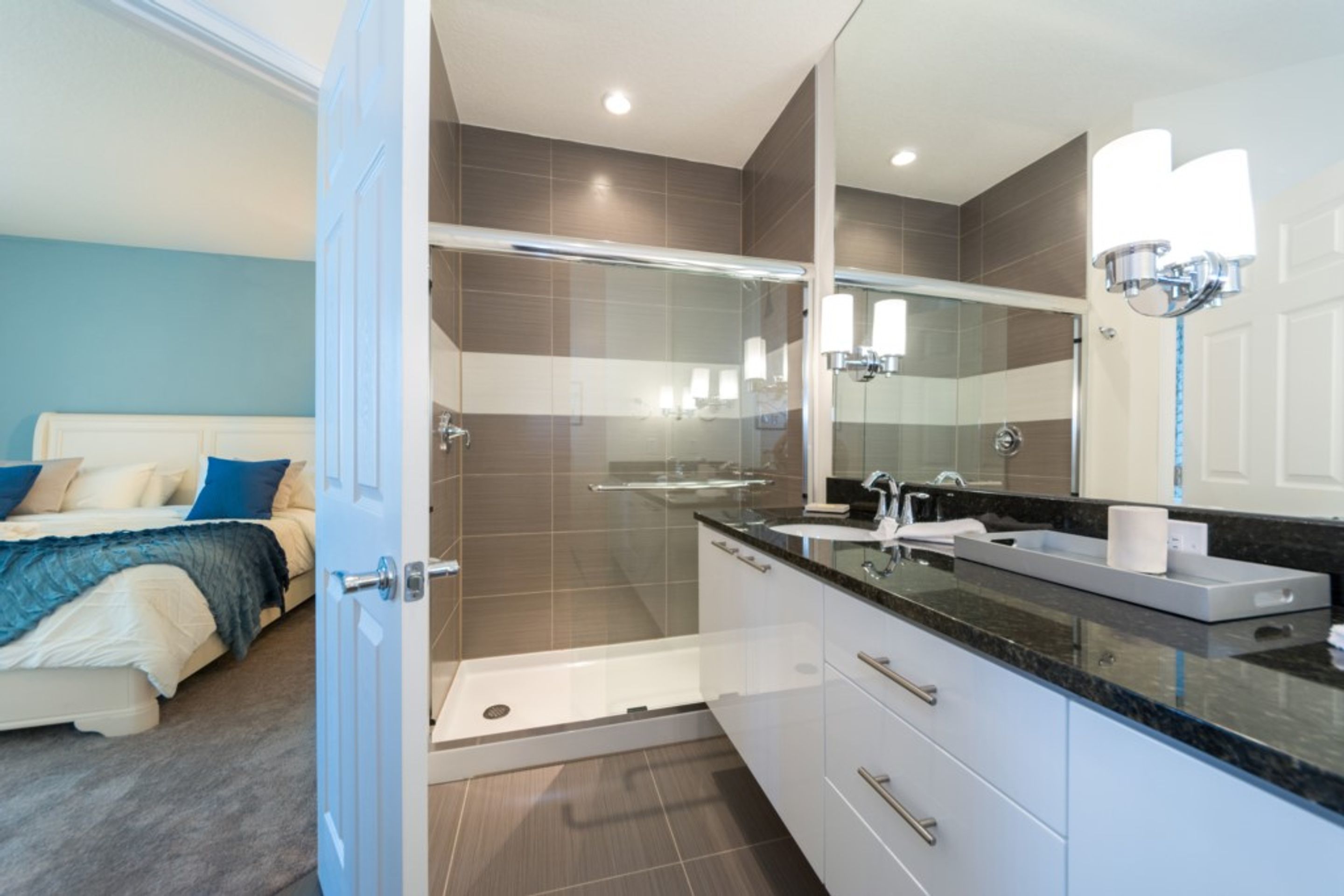 A modern bathroom with a glass shower enclosure, a large mirror, and a vanity with a sink and countertop.