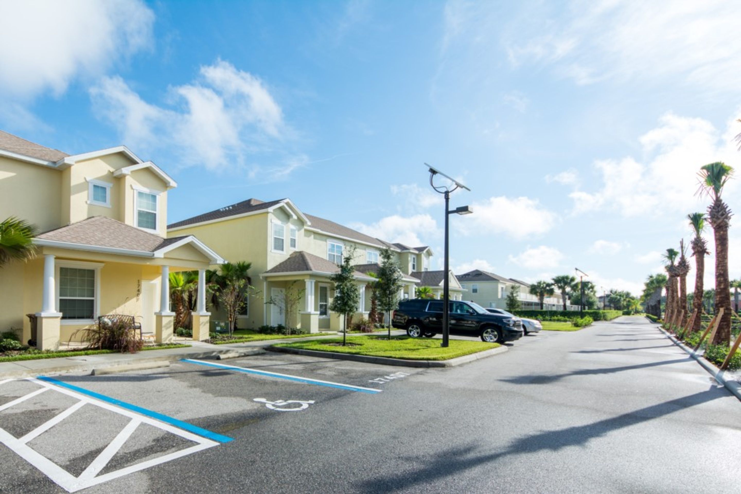 A residential street with houses, a parking lot, and a clear blue sky.