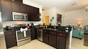 A modern kitchen with dark wood cabinets, stainless steel appliances, and a central island. - Veranda Palms 2627 (Kissimmee)