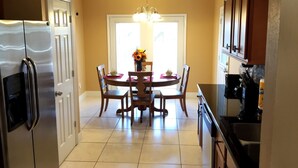 A kitchen with a dining table, chairs, a refrigerator, and cabinets. - Chatham Park 2718 (Kissimmee)