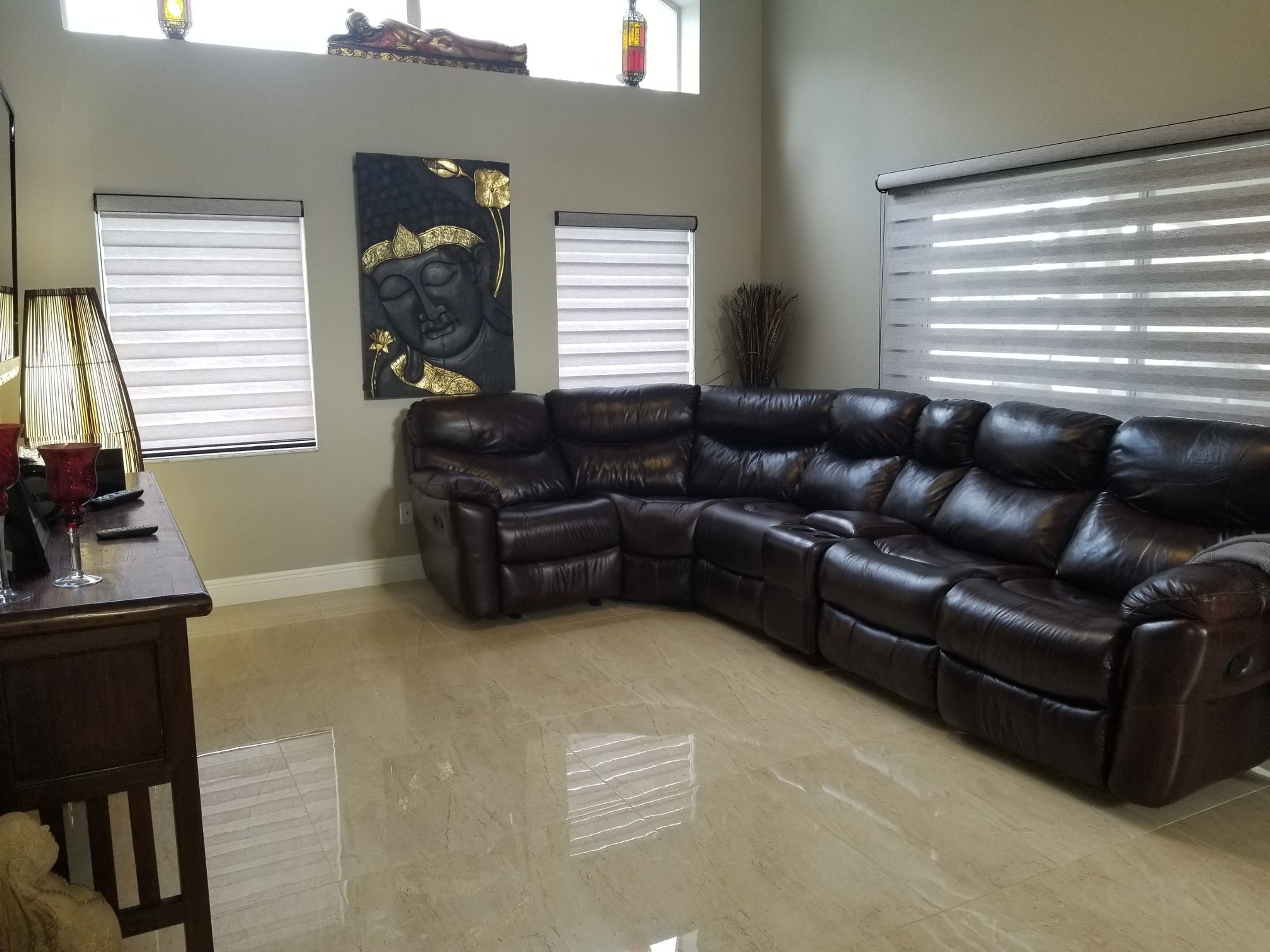 A modern living room with a dark leather sectional sofa, a wooden coffee table, and a wall-mounted artwork.