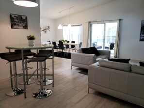 Un salon moderne avec un canapé, une table à manger et des chaises, et un coin cuisine à l’arrière-plan.