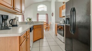 Una cocina con armarios de madera, un refrigerador de acero inoxidable y un comedor con mesa y sillas.