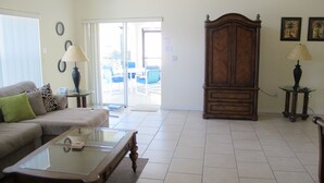 A living room with a sofa, a glass coffee table, a wooden cabinet, and a lamp. - Country Creek Estate 114 (Kissimmee)