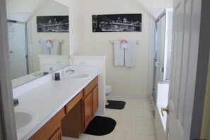 A bathroom with a white sink, mirror, and toilet. There are two black and white cityscape pictures on the wall. - Country Creek Estate 114 (Kissimmee)