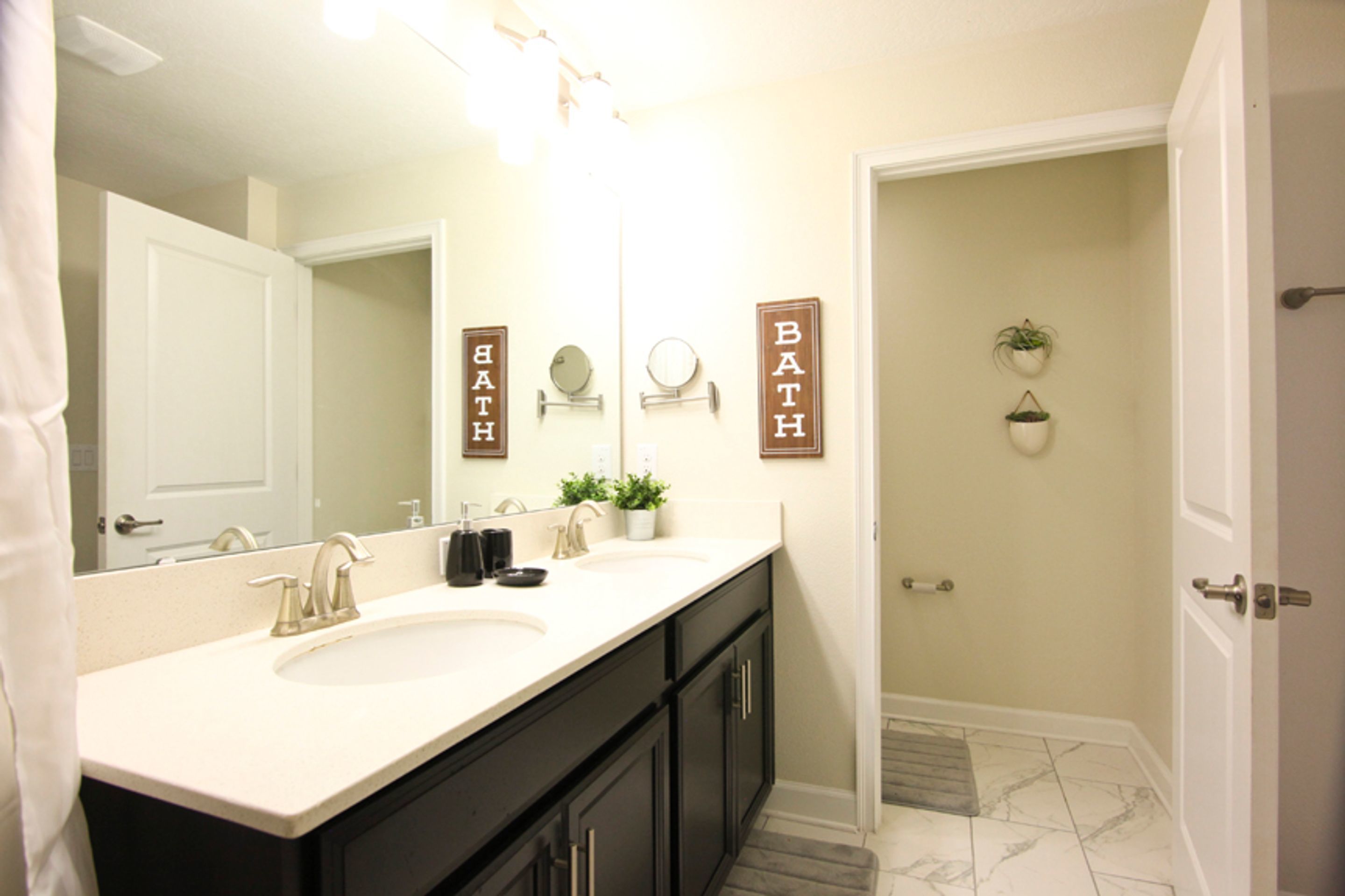 A bathroom with a white sink, black cabinets, a mirror, and two signs that read "BATH".