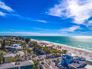 A coastal town with a beach, parked cars, and buildings with a mix of architectural styles.