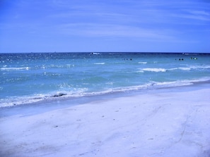 A beach with clear blue water and a sandy shore.