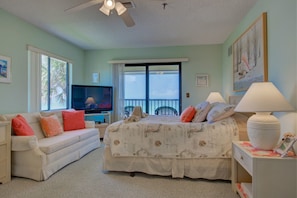 A bedroom with a bed, a sofa, a TV, and a balcony with a view.