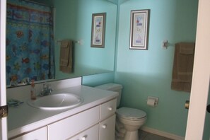 A bathroom with a white sink, a toilet, and a mirror. There are framed pictures on the wall and a towel rack. - Indian Wells 3120 (Kissimmee)