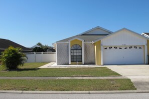 A two-story house with a garage, a small front yard, and a clear blue sky. - Indian Wells 3120 (Kissimmee)