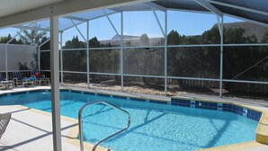 A swimming pool with a metal ladder, surrounded by a covered area with a view of trees and a mountain. - Indian Wells 3120 (Kissimmee)