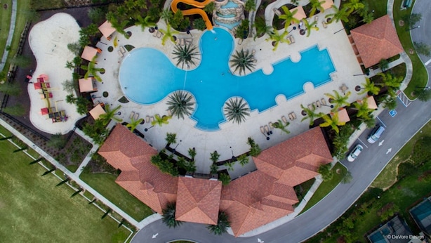 Vista aérea de un resort con una amplia piscina central, varias piscinas más pequeñas y un tobogán de agua.