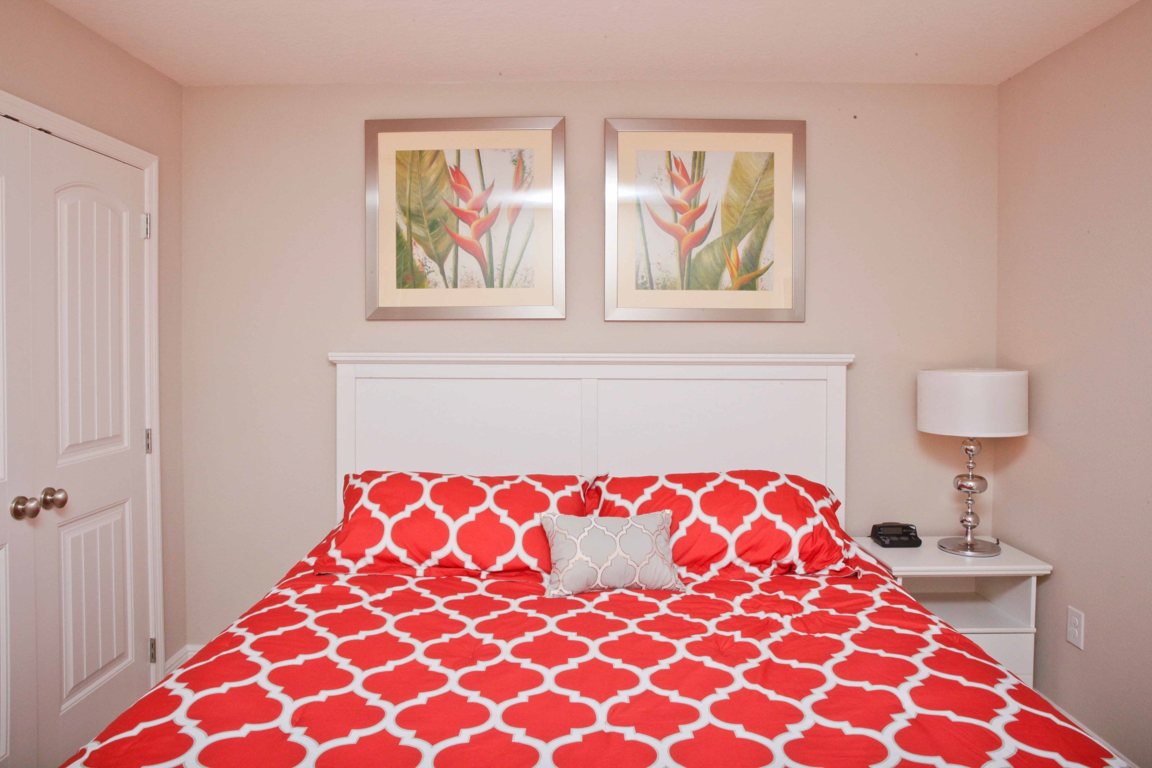 A bedroom with a bed, a nightstand, a lamp, and two framed pictures on the wall.