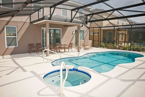 A pool area with a hot tub, lounge chairs, and a covered seating area.