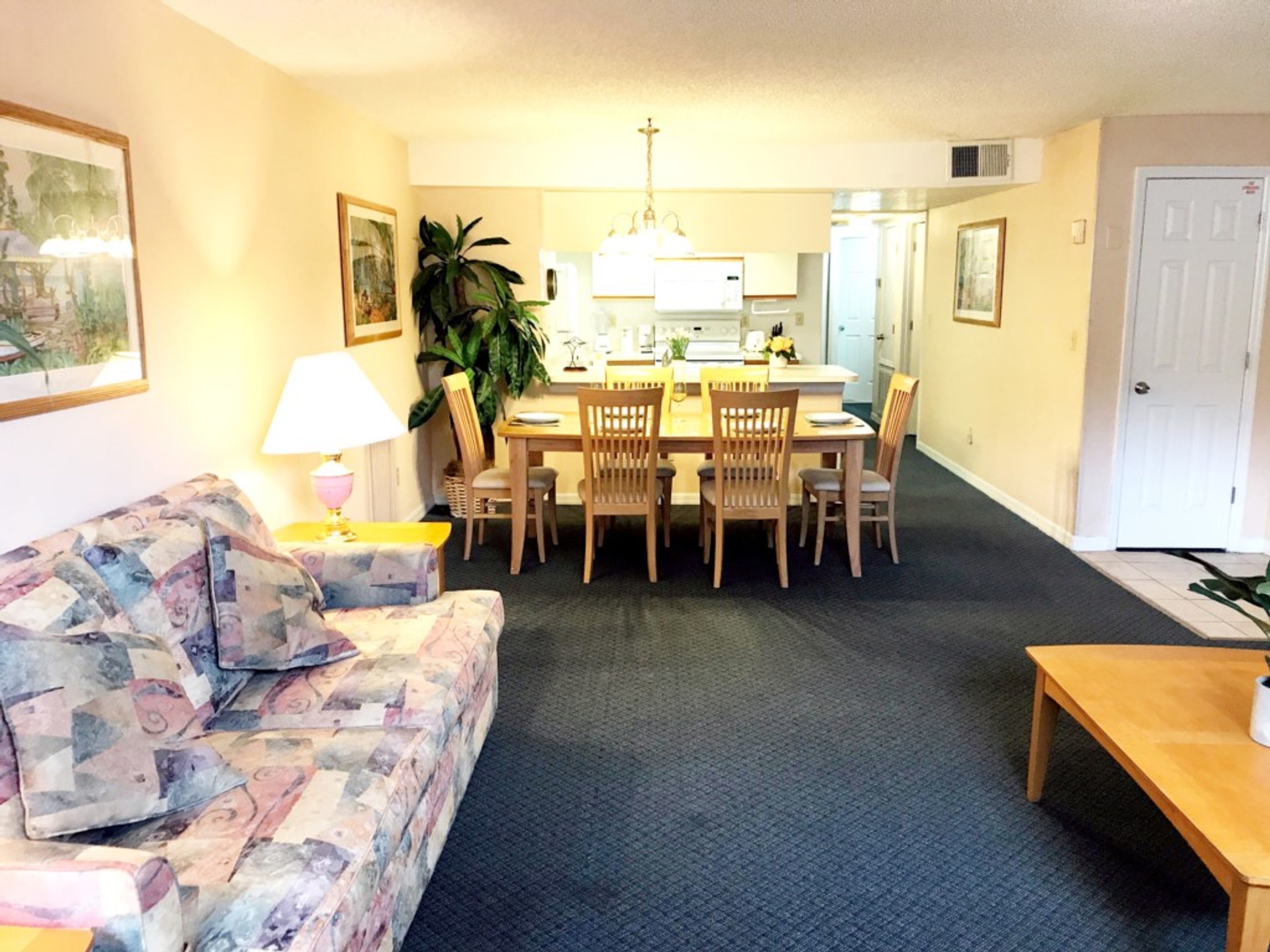 A living room with a sofa, a coffee table, and a dining area with a table and chairs.