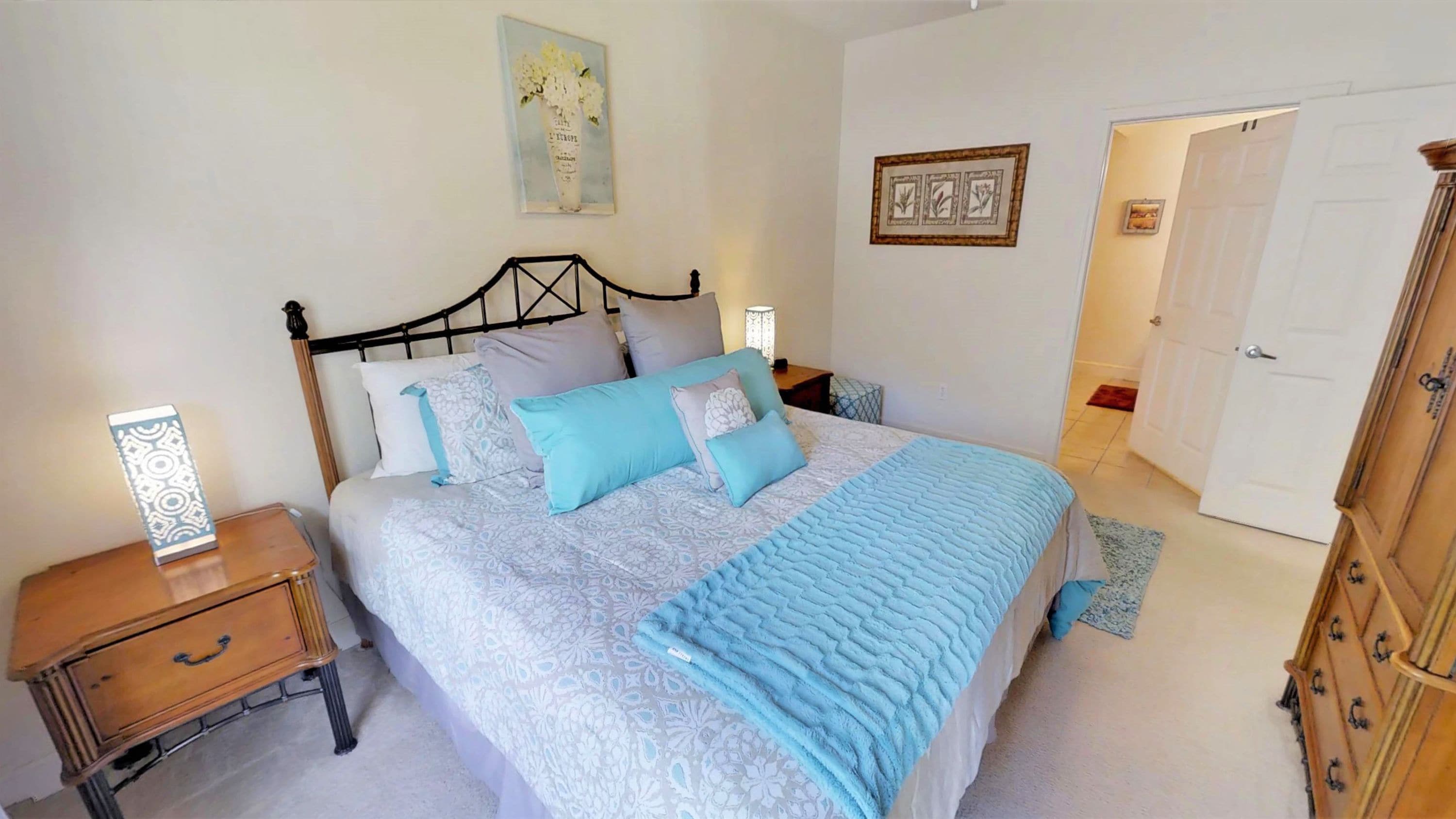 A bedroom with a bed, nightstands, a dresser, and a door.