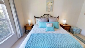 A neatly arranged bedroom with a large bed, two bedside tables, and a window with curtains.