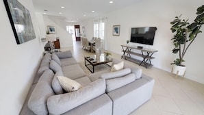 A modern living room with a large grey sectional sofa, a coffee table, and a flat-screen TV mounted on the wall. - Encore Resort at Reunion 7511 (Kissimmee)